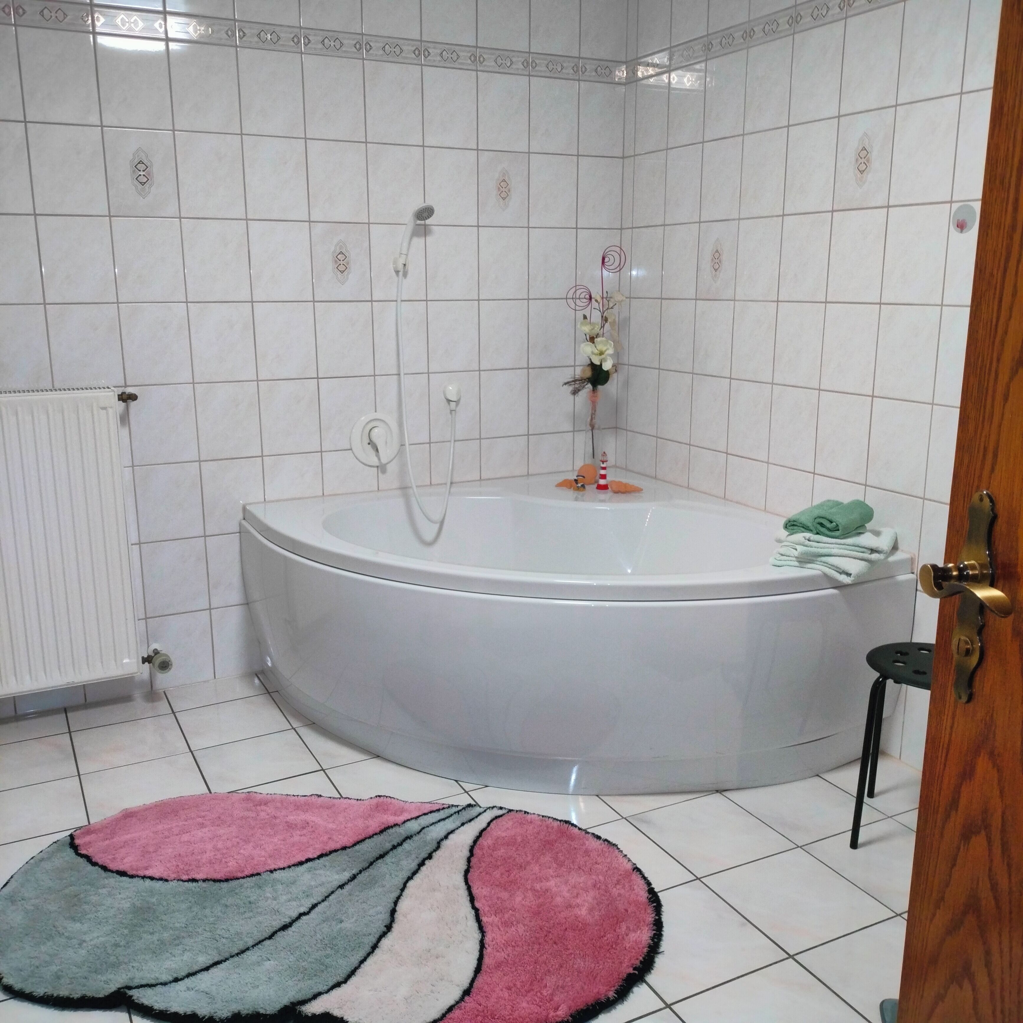 Een badkamer met een witte badkuip, een radiator en een decoratieve tegelrand.
