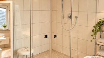 A modern bathroom with a glass-enclosed shower, a white sink, and a wooden vanity.