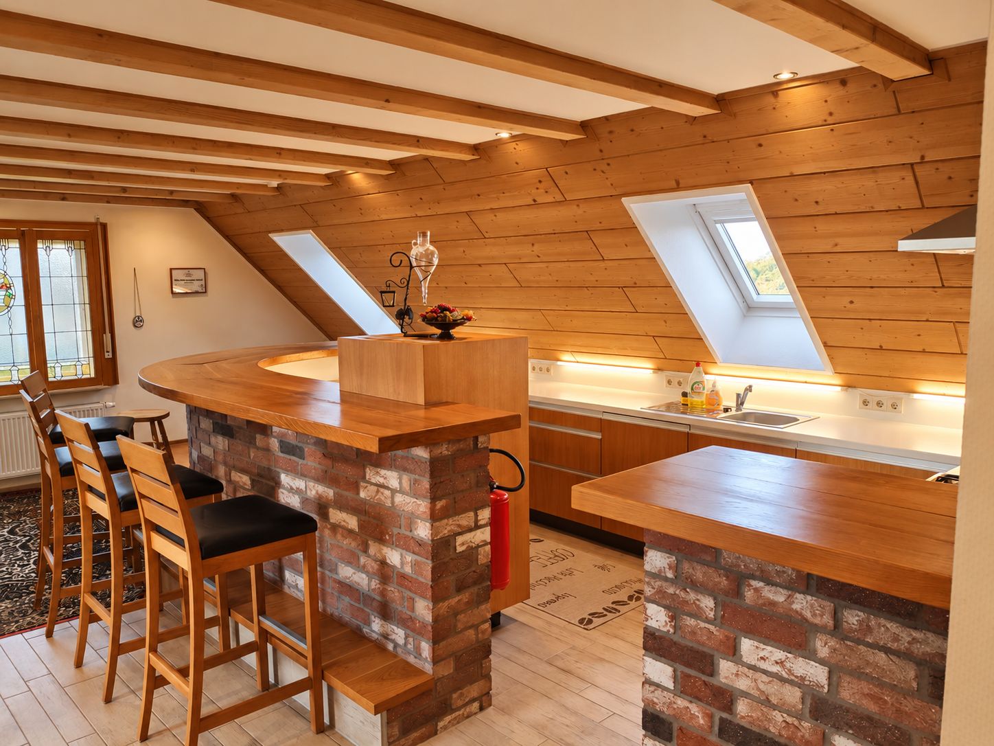 Een moderne keuken met een centraal eiland, houten balken in het plafond en een dakraam.