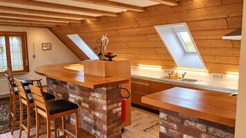 Een moderne keuken met een centraal eiland, houten balken in het plafond en een dakraam.