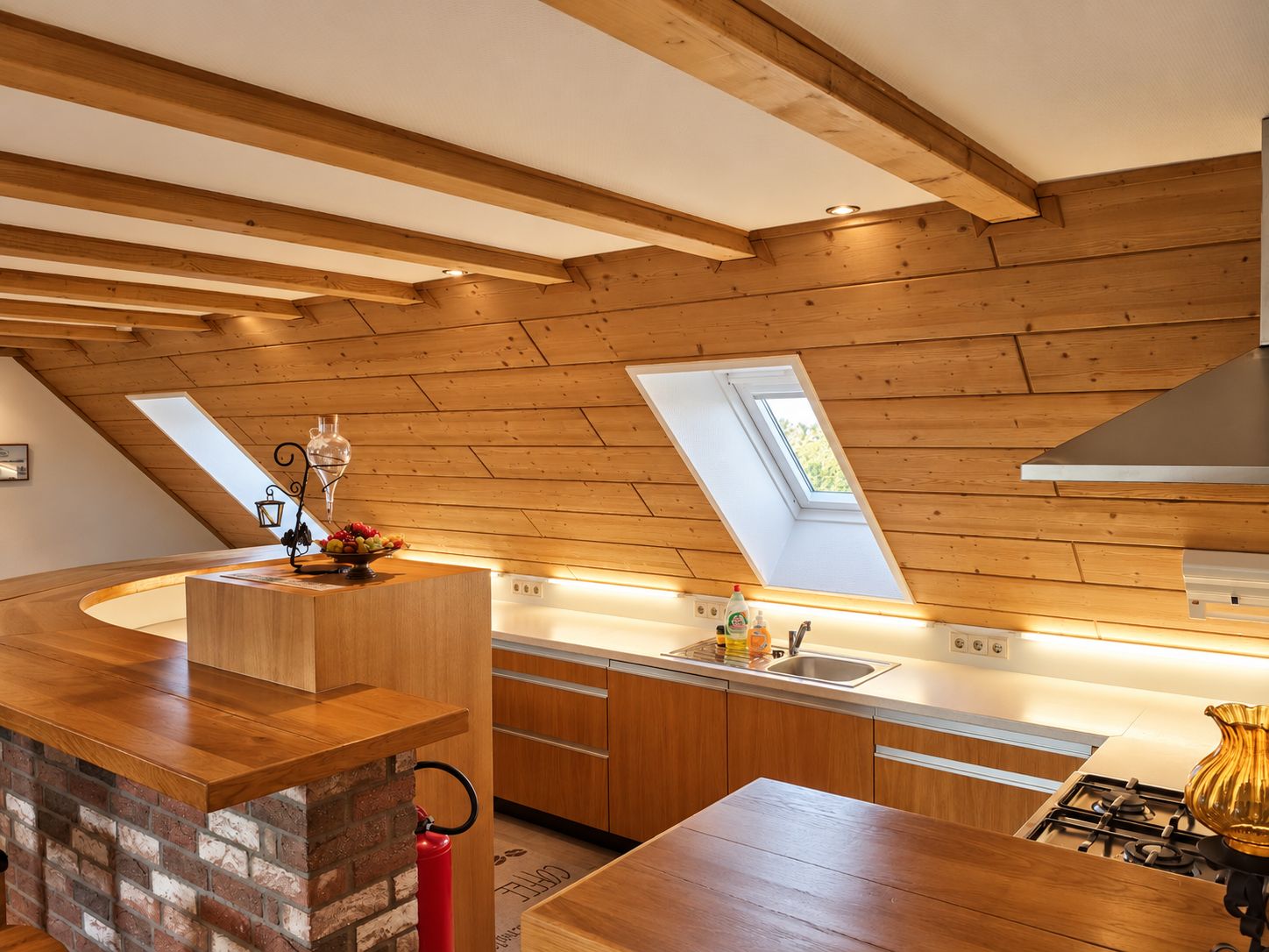 A modern kitchen with wooden beams, a skylight, and a gas stove.