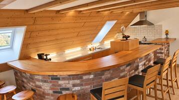 Una cocina con una isla de madera, taburetes de bar, pared de ladrillo y tragaluz.