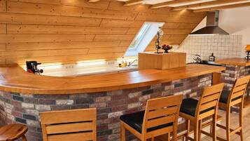 A kitchen with a wooden countertop, a brick backsplash, and a high ceiling with exposed beams.