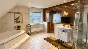A modern bathroom with a freestanding bathtub, a glass-enclosed shower, and a vanity with a sink and mirror.