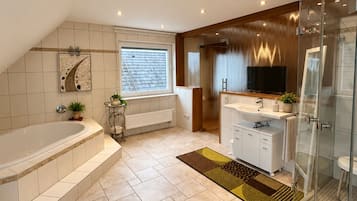 A modern bathroom with a freestanding bathtub, a glass-enclosed shower, and a vanity with a sink and mirror.