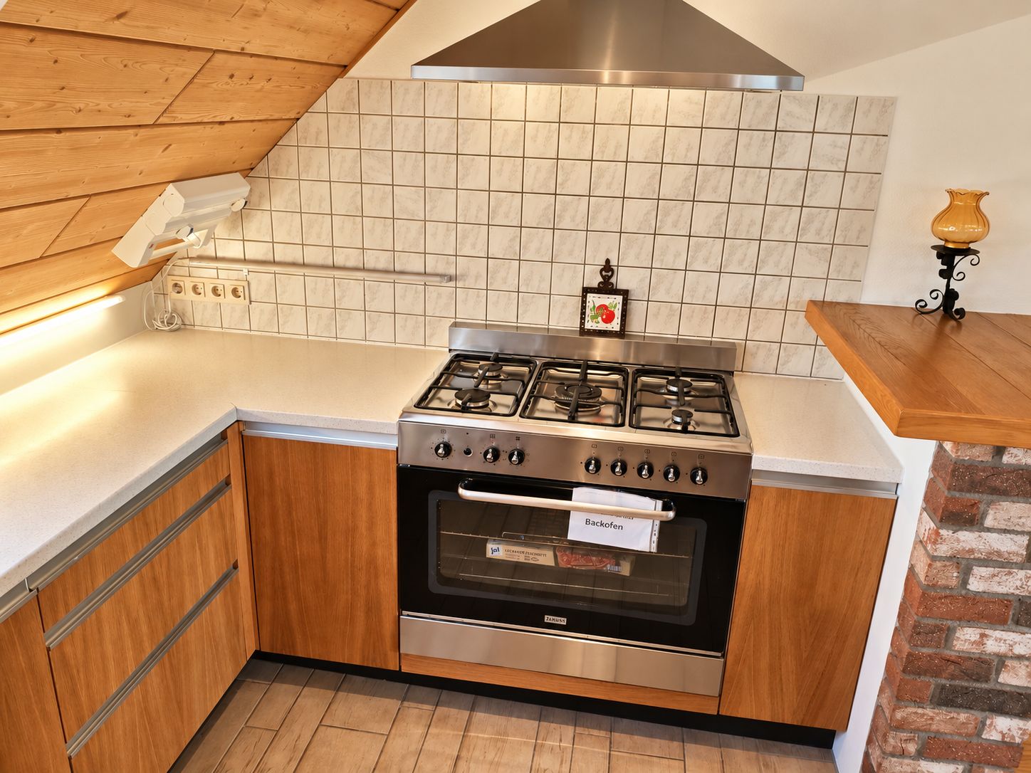 A kitchen with a gas stove, oven, wooden cabinets, and a tiled backsplash.