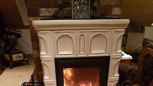 A fireplace with a fire, a brick wall, and a wooden floor.
