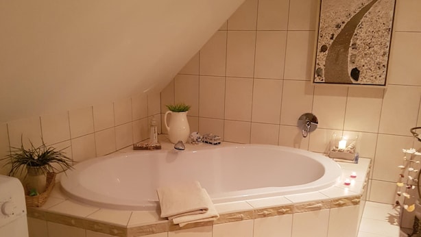 A bathroom with a freestanding bathtub, a sink, a mirror, and a potted plant.