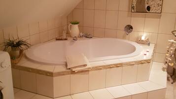 Une salle de bain avec une baignoire sur pieds, un lavabo, un miroir et une plante en pot.