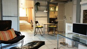 Un espacio habitable compacto con cama, sofá, zona de comedor y televisor.