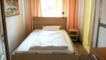 A single bed with a wooden headboard, a bedside table, and a nightstand.