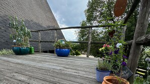 Una terraza de madera con macetas y flores.