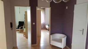 A room with a white chair, a bed with a patterned bedspread, and a wooden floor. - Frankfurt a. Experience M. - enjoy peace in the Taunus - children and dogs welcome (Schmitten)