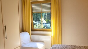 A bedroom with a bed, a wardrobe, a window with curtains, and a radiator. - Frankfurt a. Experience M. - enjoy peace in the Taunus - children and dogs welcome (Schmitten)