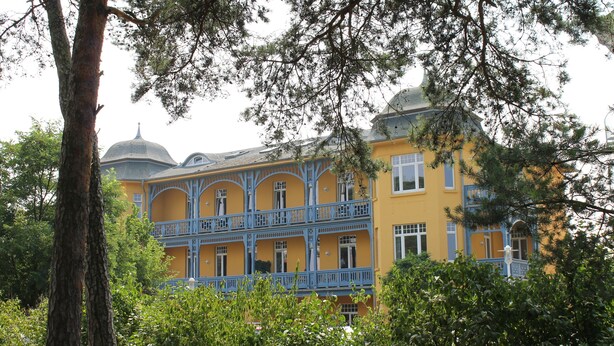 Ein mehrstöckiges Gebäude mit gelber Fassade und blauen Balkonen.
