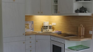 Eine kompakte Küche mit Kaffeemaschine, Backofen und einer Küchenzeile mit Geschirr.