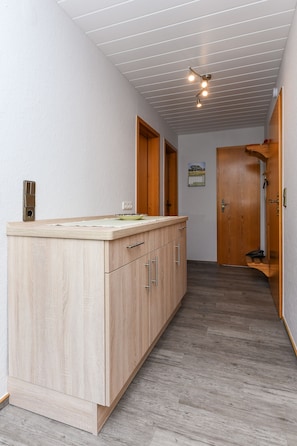 Ein Flur mit einem Holzkasten, einer Tür und einer Leuchte.