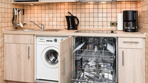 A compact kitchen with wooden cabinets, a microwave, a coffee maker, and a dishwasher.