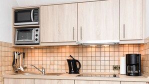 A modern kitchen with wooden cabinets, a microwave, a coffee maker, and a sink.