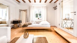 A bedroom with a wooden bed, a white sofa, a small table, and a window with curtains.
