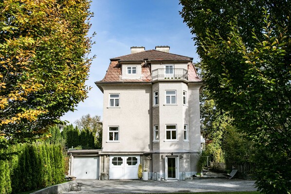 Ein mehrgeschossiges Gebäude mit einem zentralen Eingang, großen Fenstern und einer Garage.