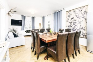 Ein Essbereich mit einem Holztisch, acht Stühlen und einem weißen Sofa.