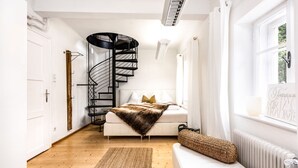 A modern bedroom with a spiral staircase, a white sofa, and a large window.
