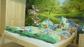 Een slaapkamer met een bed, een houten kledingkast en een grote muurschildering met natuurmotieven.