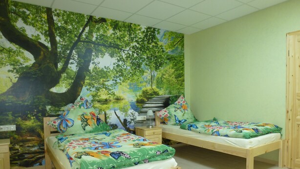 Een kamer met twee houten bedden, elk met een kleurrijk beddegoed met vlinderthema.