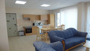 Een compacte woonruimte met een kitchenette, een eetgedeelte en een zithoek met twee banken.