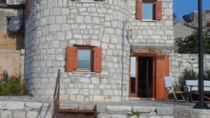 A stone building with a curved facade, wooden shutters, and a small staircase leading to the entrance. - unique historical STONE TOWER DIRECTLY BY THE SEA! carefully restored (Umag)