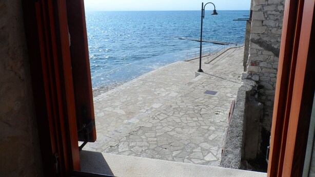 A stone-paved walkway leading to a coastal area with a clear view of the sea. - unique historical STONE TOWER DIRECTLY BY THE SEA! carefully restored (Umag)