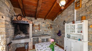 Una habitación rústica con paredes de piedra, chimenea, techo de madera y un armario blanco con puertas de cristal.