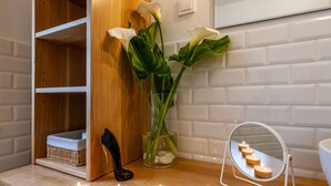 Un baño con repisa de madera, un florero con flores, un espejo y varias velas encendidas.