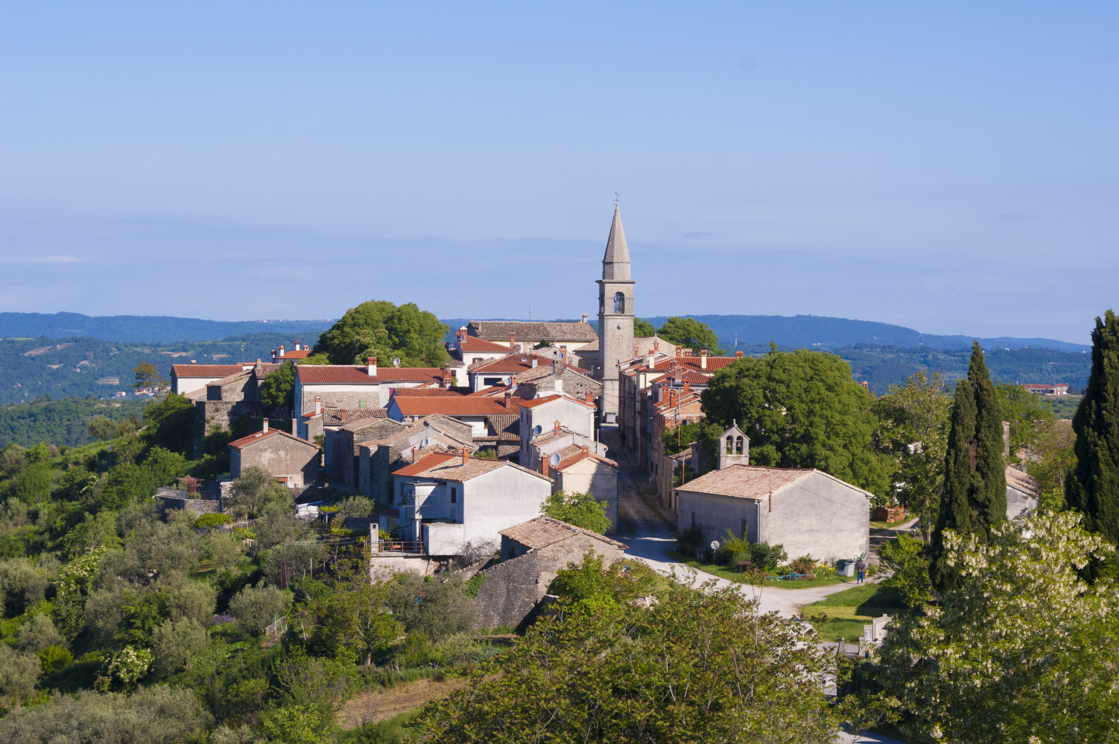 A historic town with a prominent church tower, surrounded by traditional buildings and lush greenery.