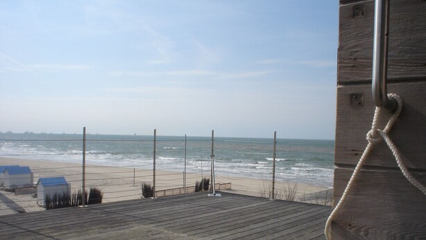 A wooden deck with a view of the beach and ocean. - Bright vacation home for up to 6 people with fireplace, garden, parking and WiFi in De Haan (De Haan)