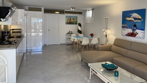 A modern living room with a sofa, a glass coffee table, and a dining area with chairs and a table. - Beautiful apartment in the nature reserve "Risco del Paso" ideal for nature lovers (Costa Calma)