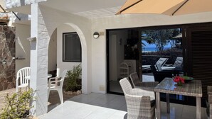 A modern outdoor patio with wicker furniture, a glass table, and a view of the sea. - Beautiful apartment in the nature reserve "Risco del Paso" ideal for nature lovers (Costa Calma)