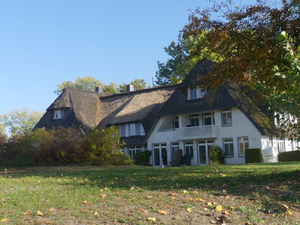 Une grande maison à deux étages, dotée d’un toit à forte pente, d’un balcon à l’étage supérieur et d’une pelouse bien entretenue à l’avant.
