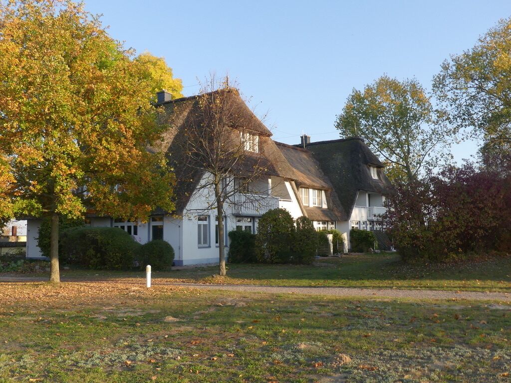 A traditional house with a steeply pitched roof, surrounded by a well-maintained lawn and trees.