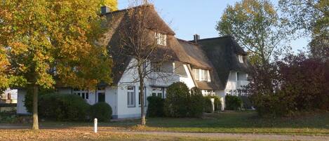 A traditional house with a steeply pitched roof, surrounded by a well-maintained lawn and trees.