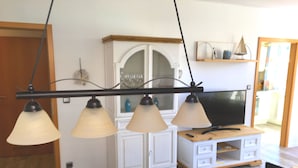 Un comedor con una mesa de madera, un armario blanco y un televisor sobre un mueble de madera.
