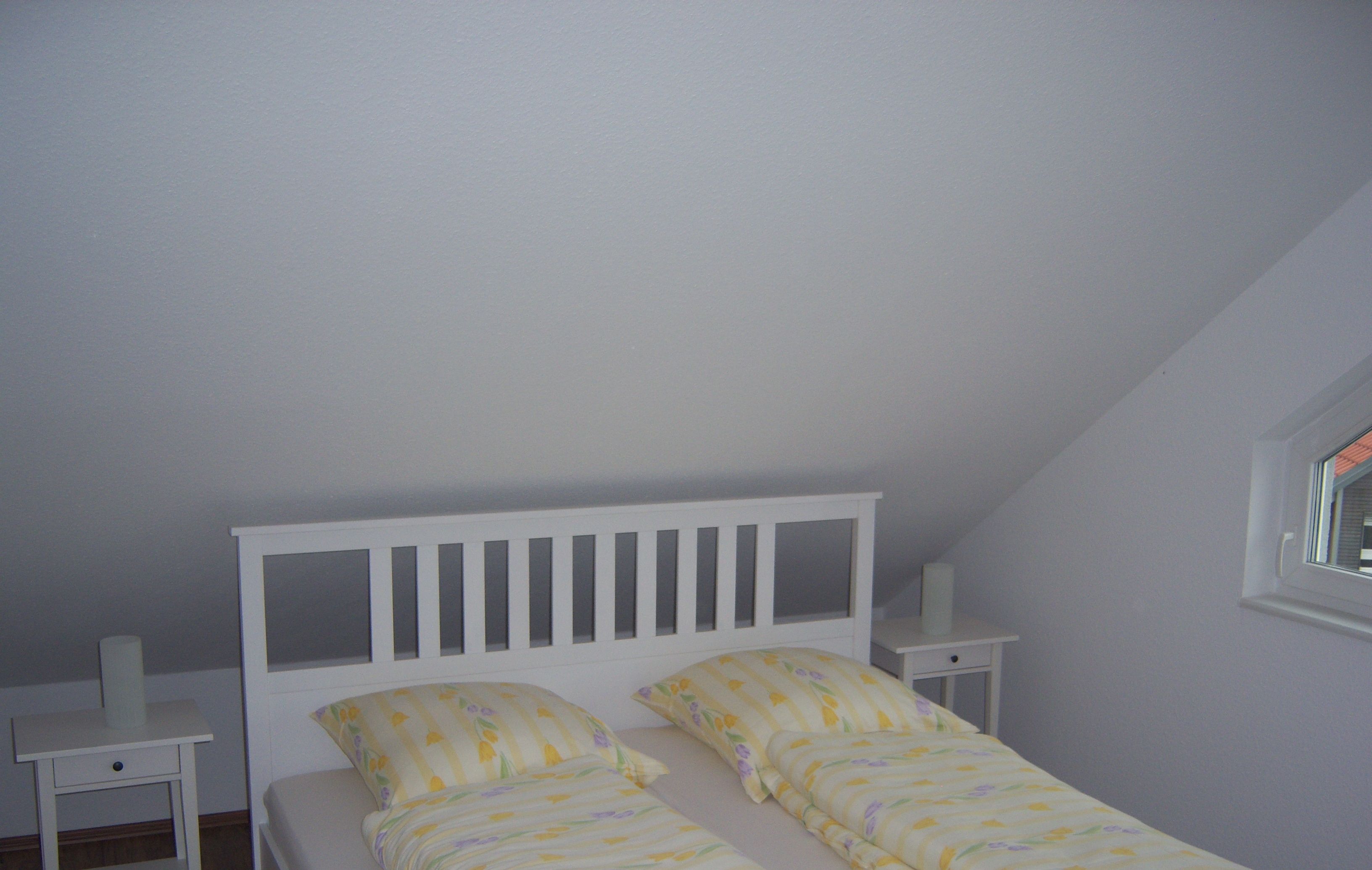 Un lit simple avec une tête de lit blanche et deux tables de chevet de chaque côté.