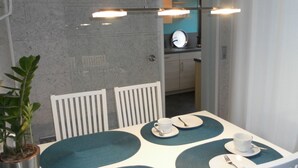 A dining area with a table set for four, a potted plant, and a view into the kitchen. - Welcome Holiday home Schmitz No. 2, for 2 to 4 people.  with Wi-Fi (Pünderich/Mosel)