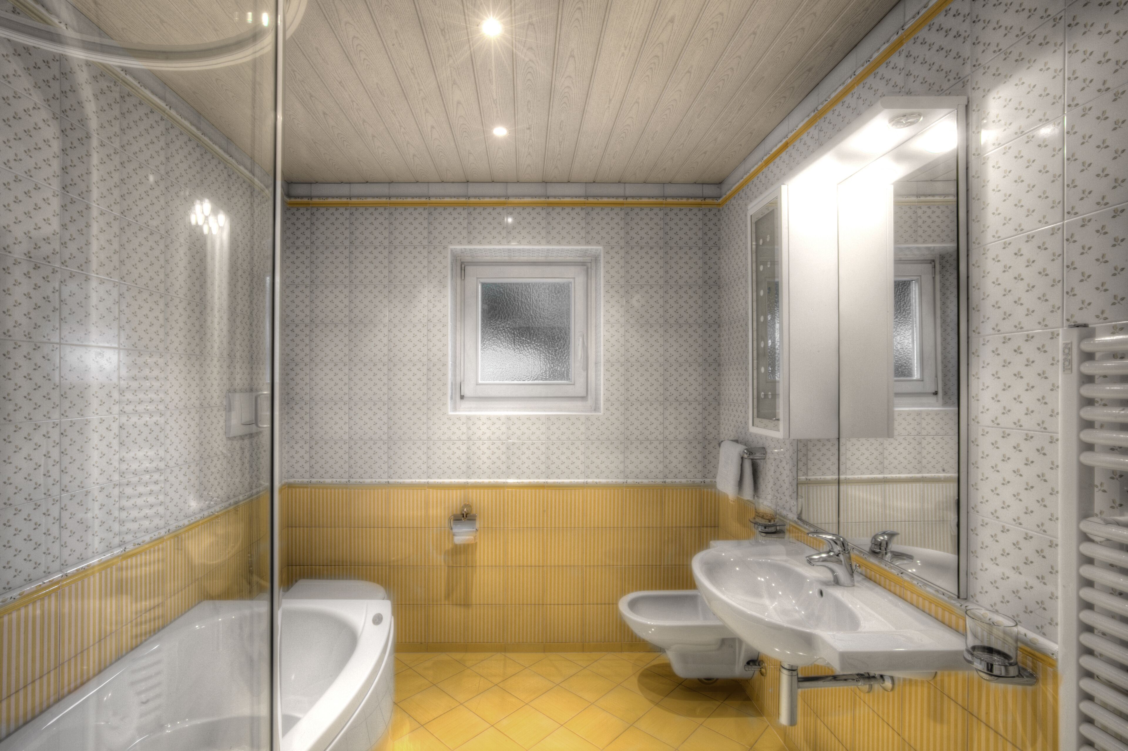 A bathroom with a bathtub, two sinks, a toilet, and a mirror.