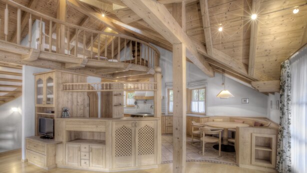Une cuisine spacieuse avec des meubles de rangement en bois, un coin repas et un escalier intégré.