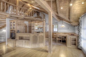 Een ruime keuken met houten kasten, een eethoek en een ingebouwde trap.