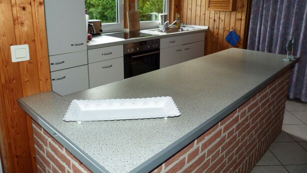 A kitchen with a granite countertop, a built-in oven, and a window with a view of greenery.
