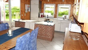 A compact kitchen with a brick island, white cabinets, and a dining area with blue chairs.