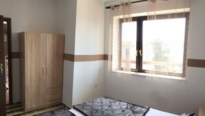 Un dormitorio con cama, armario y ventana con cortinas.